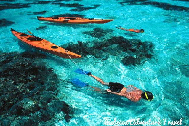 Travelers snorkeling in the turquoise water in Gardner Bay